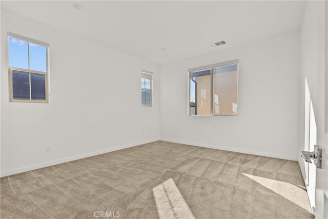 carpeted spare room with visible vents and baseboards