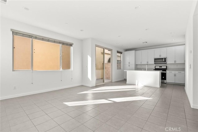 kitchen featuring stainless steel appliances, open floor plan, white cabinetry, and light tile patterned floors