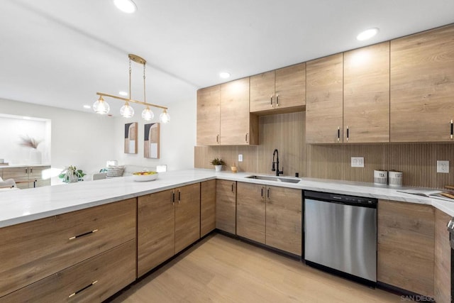 kitchen featuring sink, light stone counters, light hardwood / wood-style flooring, stainless steel dishwasher, and hanging light fixtures