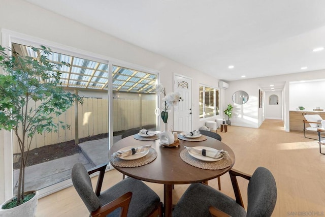 dining area with a wall unit AC and light wood-type flooring