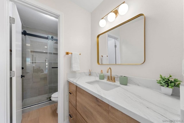 bathroom featuring toilet, wood-type flooring, walk in shower, and vanity