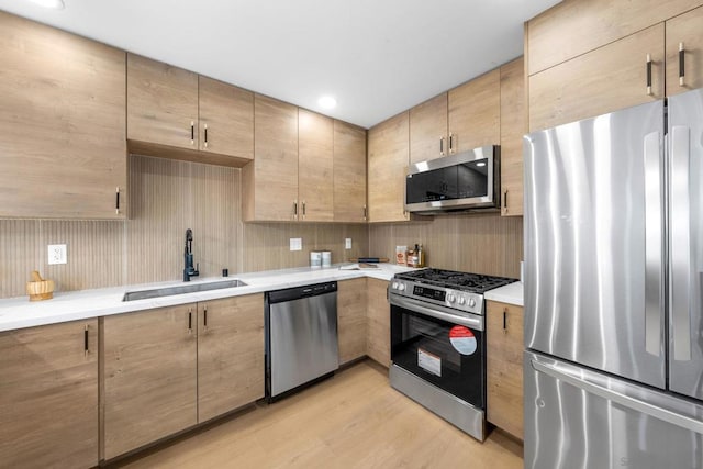 kitchen with light hardwood / wood-style flooring, sink, stainless steel appliances, backsplash, and light brown cabinets