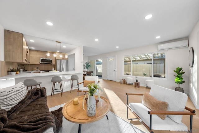 living room with sink, light hardwood / wood-style flooring, and an AC wall unit