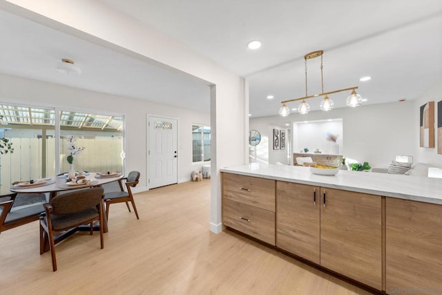 kitchen featuring light stone counters, light hardwood / wood-style floors, and hanging light fixtures