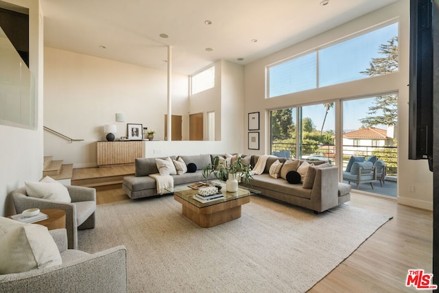 living room with light hardwood / wood-style flooring and a towering ceiling