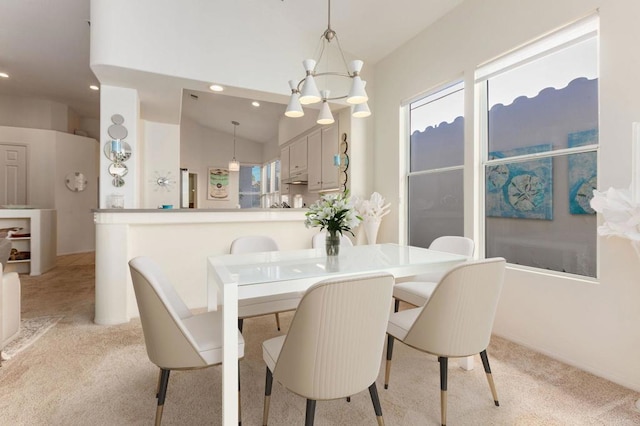 dining room with an inviting chandelier, vaulted ceiling, and light carpet