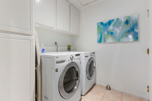 clothes washing area featuring washer and dryer, cabinets, and light tile patterned floors