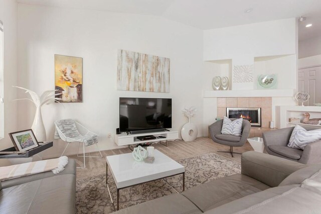 living room featuring a tile fireplace and vaulted ceiling