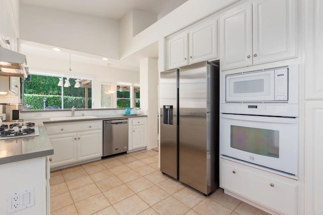 kitchen featuring white cabinets, appliances with stainless steel finishes, light tile patterned flooring, and sink