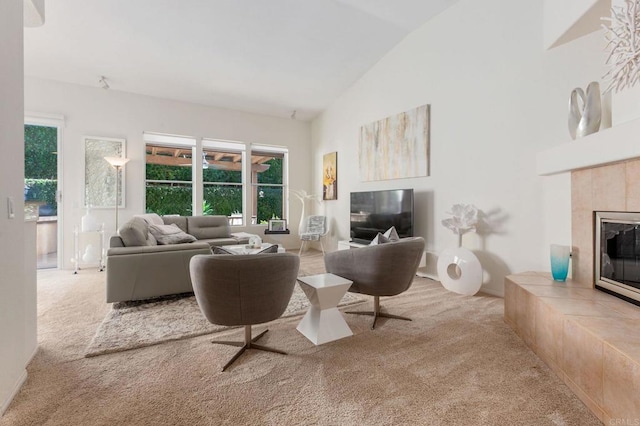 living room with a tiled fireplace, light carpet, and vaulted ceiling