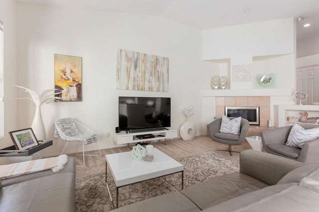 living room with a tiled fireplace and vaulted ceiling