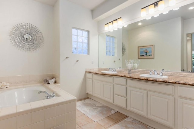 bathroom with tile patterned flooring, a relaxing tiled tub, and vanity