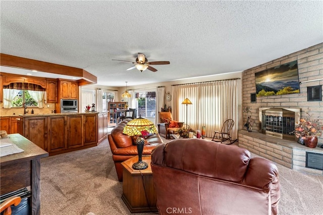 living room featuring a textured ceiling, ceiling fan, a healthy amount of sunlight, and light colored carpet