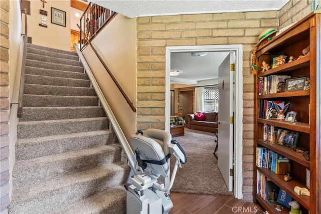 staircase with a textured ceiling and brick wall