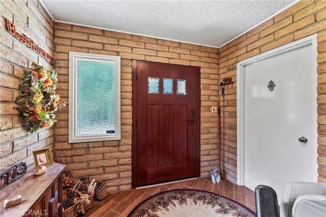 entryway featuring brick wall and a textured ceiling