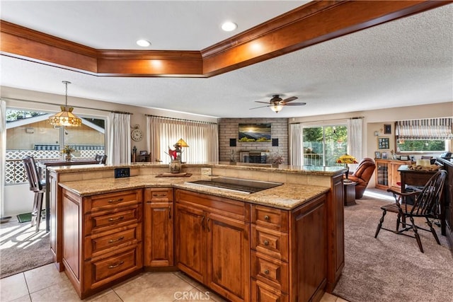 kitchen featuring ceiling fan, black electric cooktop, light colored carpet, hanging light fixtures, and a large island with sink