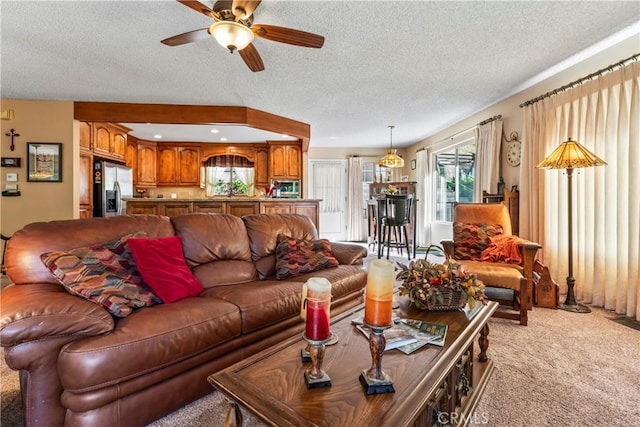 living room featuring ceiling fan, light colored carpet, and a textured ceiling