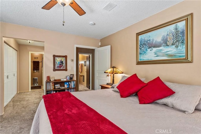 bedroom with ceiling fan, light colored carpet, and a textured ceiling