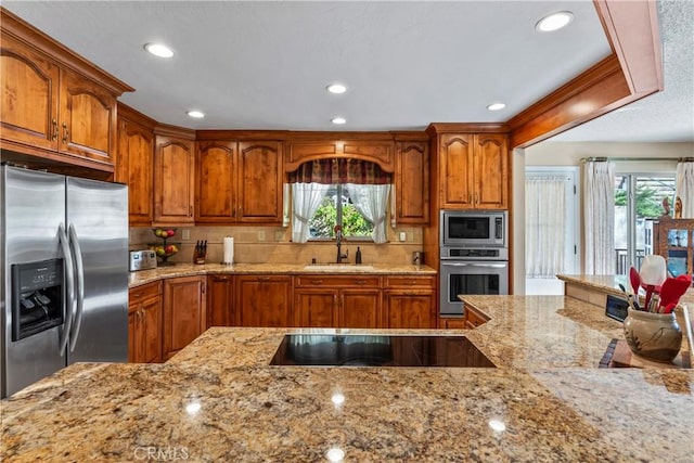 kitchen with plenty of natural light, sink, light stone counters, and stainless steel appliances