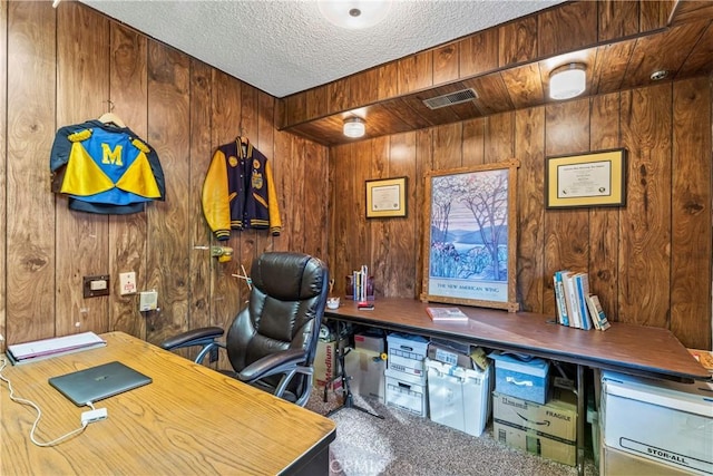 carpeted office featuring a textured ceiling and wooden walls