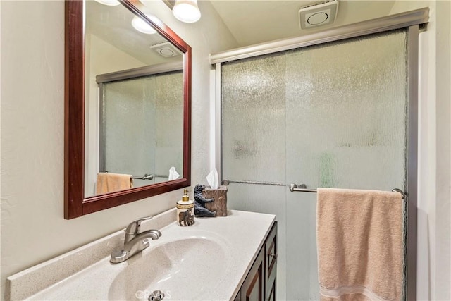 bathroom with a shower with shower door and vanity