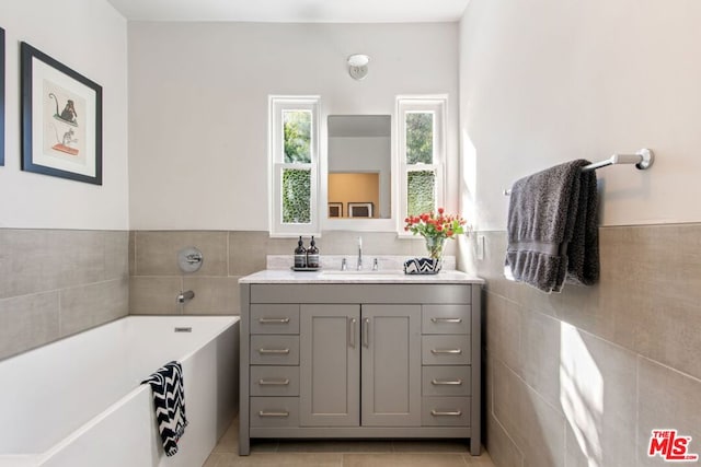 bathroom featuring tile walls, a washtub, tile patterned flooring, and vanity