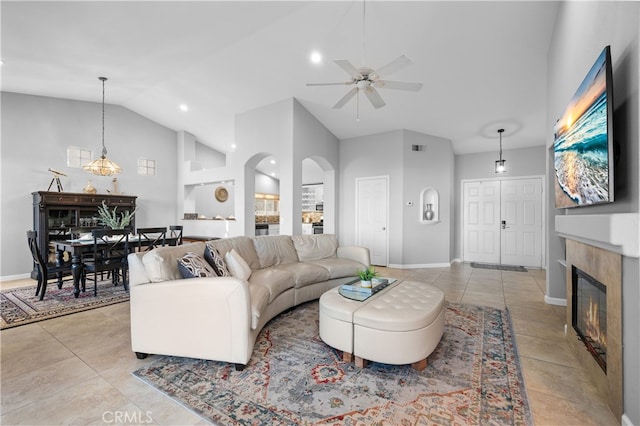 living room with high vaulted ceiling, a tiled fireplace, and ceiling fan