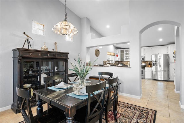 dining area featuring a towering ceiling, light tile patterned floors, and a notable chandelier