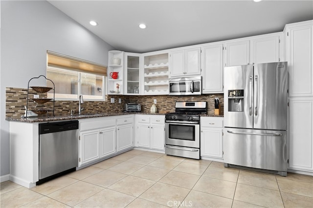 kitchen featuring appliances with stainless steel finishes, dark stone counters, sink, white cabinetry, and tasteful backsplash