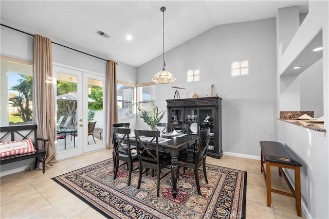 dining room featuring lofted ceiling, french doors, light tile patterned floors, and a chandelier