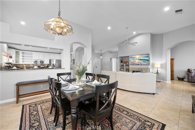 tiled dining area with ceiling fan with notable chandelier and high vaulted ceiling