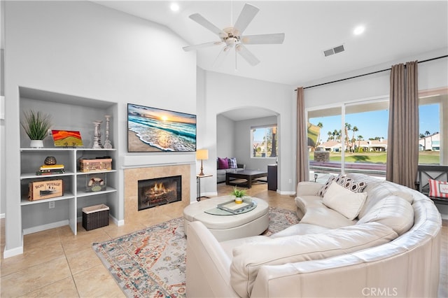 tiled living room featuring lofted ceiling, a fireplace, and ceiling fan