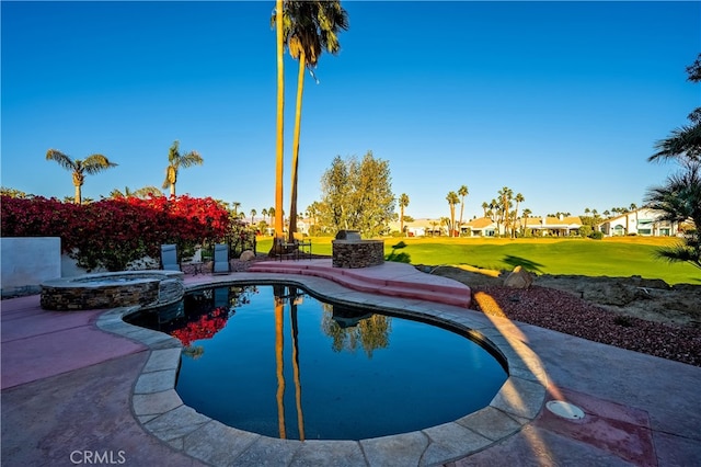 view of pool featuring a yard, an in ground hot tub, exterior kitchen, and a patio