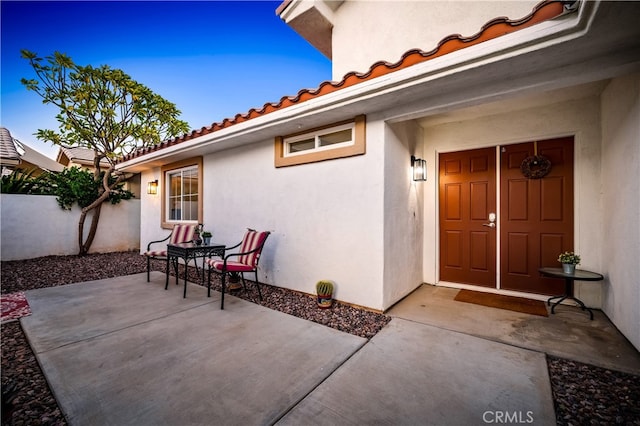 exterior entry at dusk featuring a patio