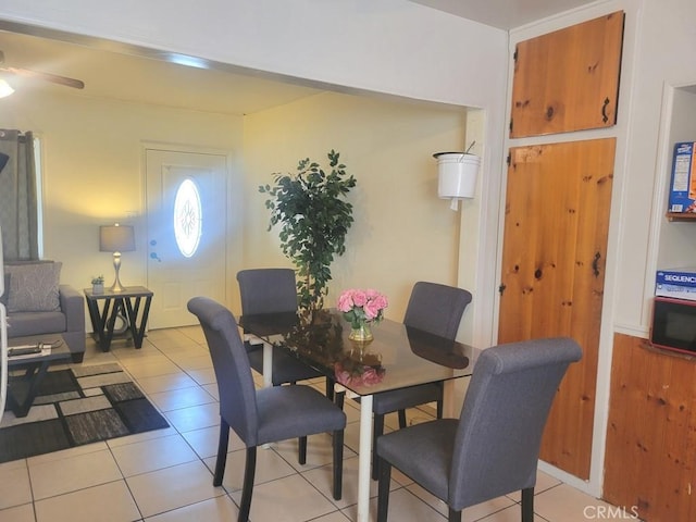 tiled dining area with ceiling fan and wood walls