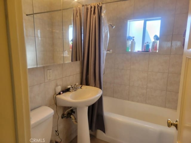 bathroom featuring toilet, tile walls, and shower / bath combo