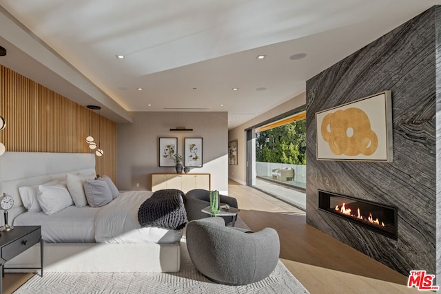 bedroom with a fireplace, wooden walls, and access to exterior