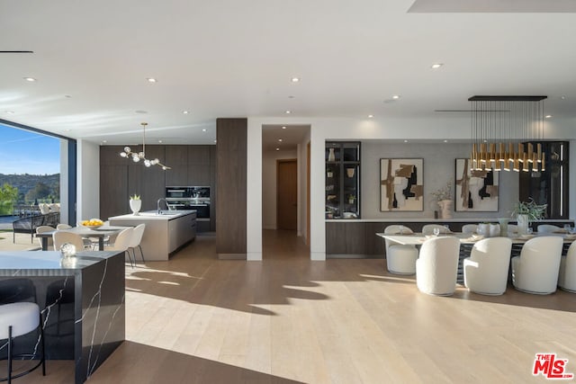 interior space featuring sink, light wood-type flooring, expansive windows, and an inviting chandelier