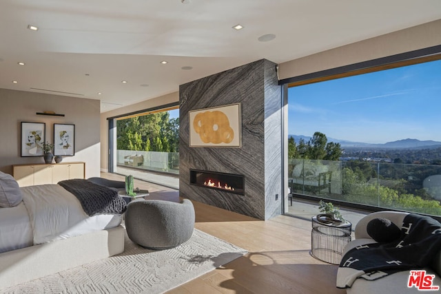 bedroom featuring a high end fireplace, light hardwood / wood-style floors, and a mountain view