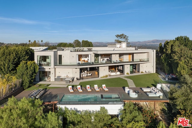 rear view of property with a patio area, a lawn, and a hot tub