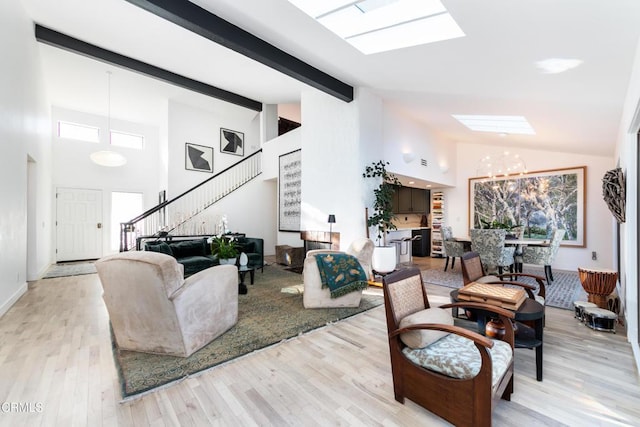 living room featuring high vaulted ceiling, a skylight, a notable chandelier, light hardwood / wood-style floors, and beam ceiling