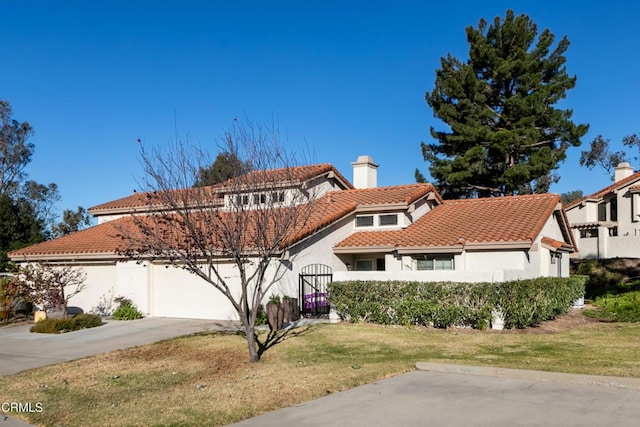 mediterranean / spanish house featuring a tile roof, a chimney, stucco siding, an attached garage, and driveway