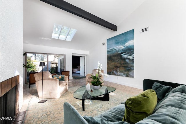 living area with vaulted ceiling with skylight, a fireplace with flush hearth, wood finished floors, visible vents, and baseboards