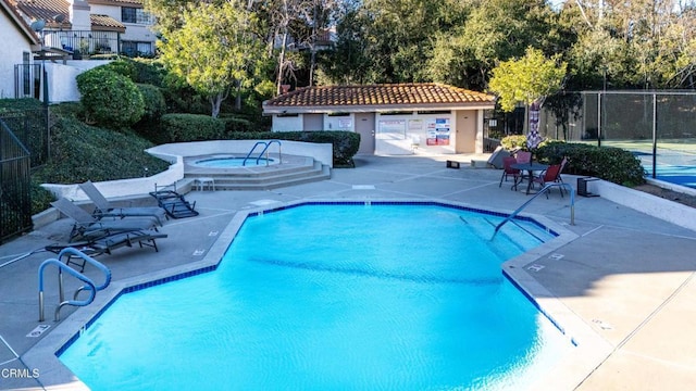 community pool featuring a patio, fence, and a hot tub