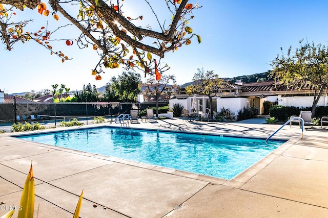 community pool with a patio area and fence