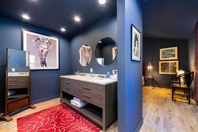 bathroom featuring double vanity, recessed lighting, a sink, wood finished floors, and baseboards