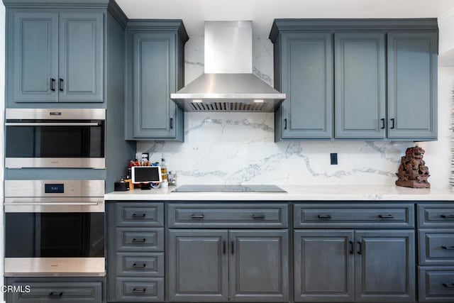 kitchen featuring wall chimney range hood, double oven, black electric cooktop, and decorative backsplash