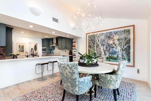 dining room with lofted ceiling, recessed lighting, a notable chandelier, visible vents, and light wood-style floors