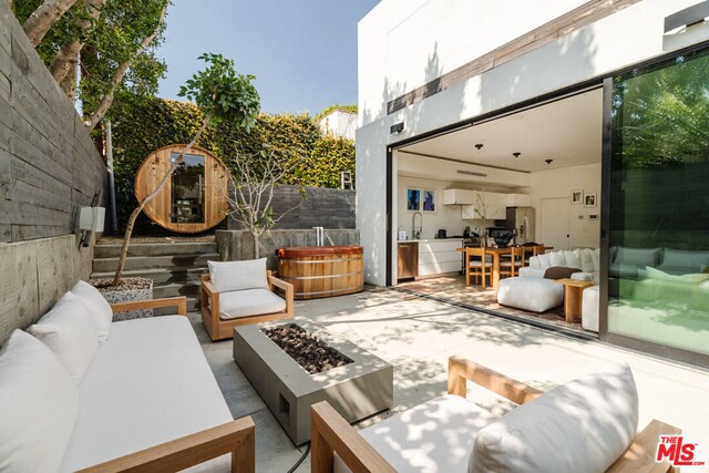 view of patio / terrace featuring sink, an outdoor living space with a fire pit, and a hot tub