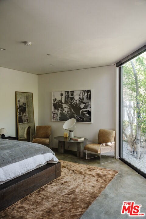 bedroom featuring concrete flooring, access to outside, and expansive windows